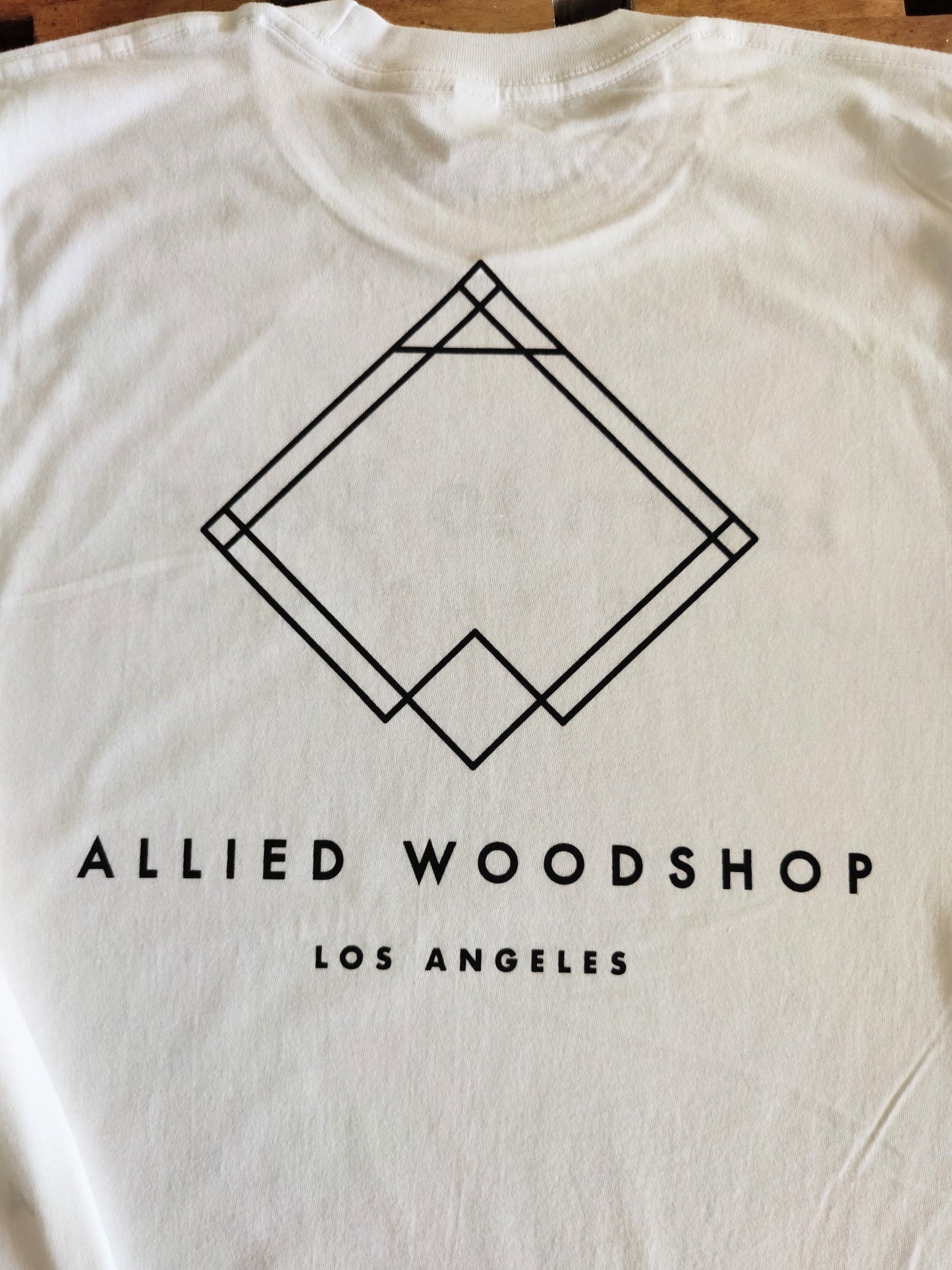 back of shirt. White shirt with black printed Allied Woodshop Los Angeles logo and text.