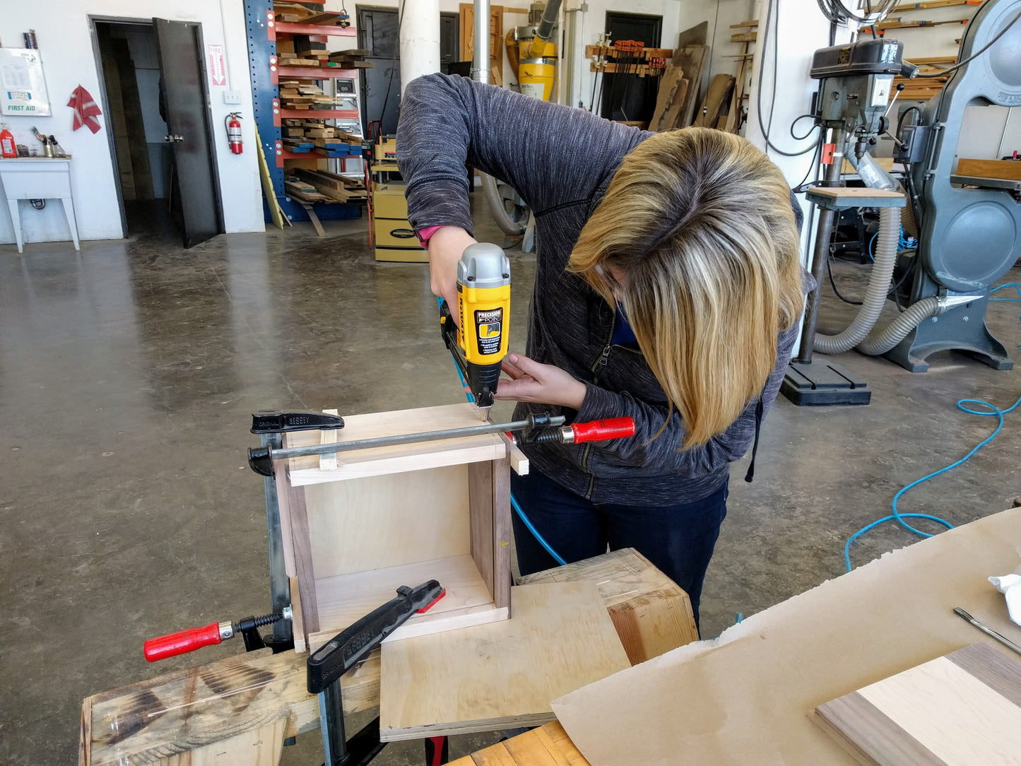Woodworking student drills into her clamped woodworking project