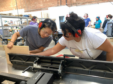 a teacher helping a student use a jointer