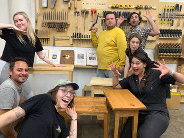 Seven people in silly poses around some wood tables